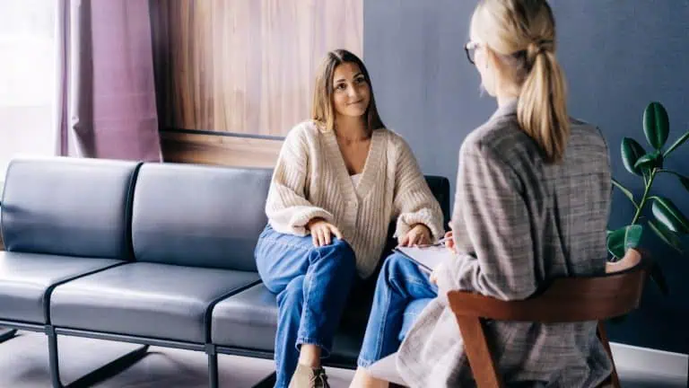 A smiling client is having a confidential conversation with a consultant psychologist. A smiling client is having a confidential conversation with a consultant psychologist