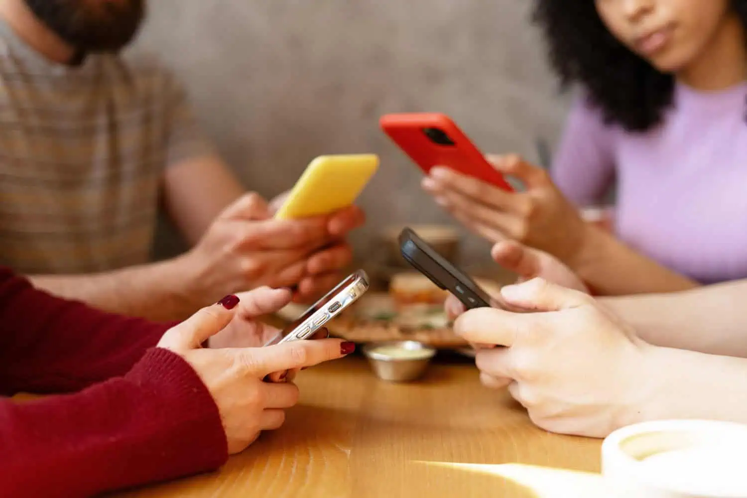 Friends using smartphones while having lunch together at restaurant