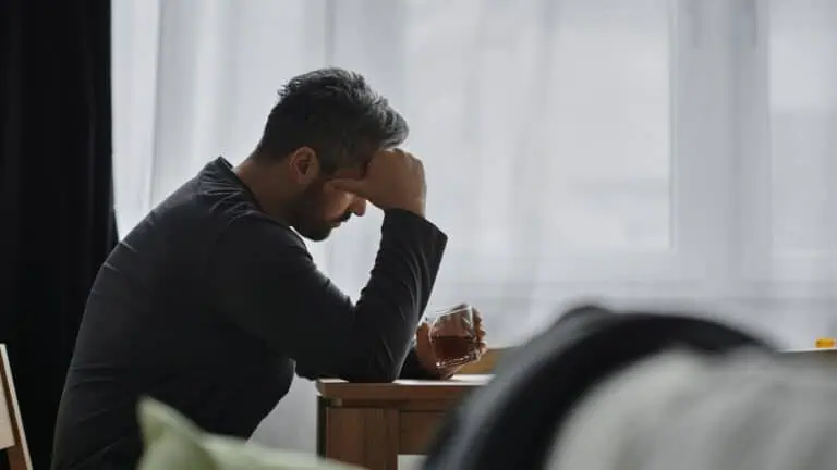 Sad Man with a Drink Sits near Window