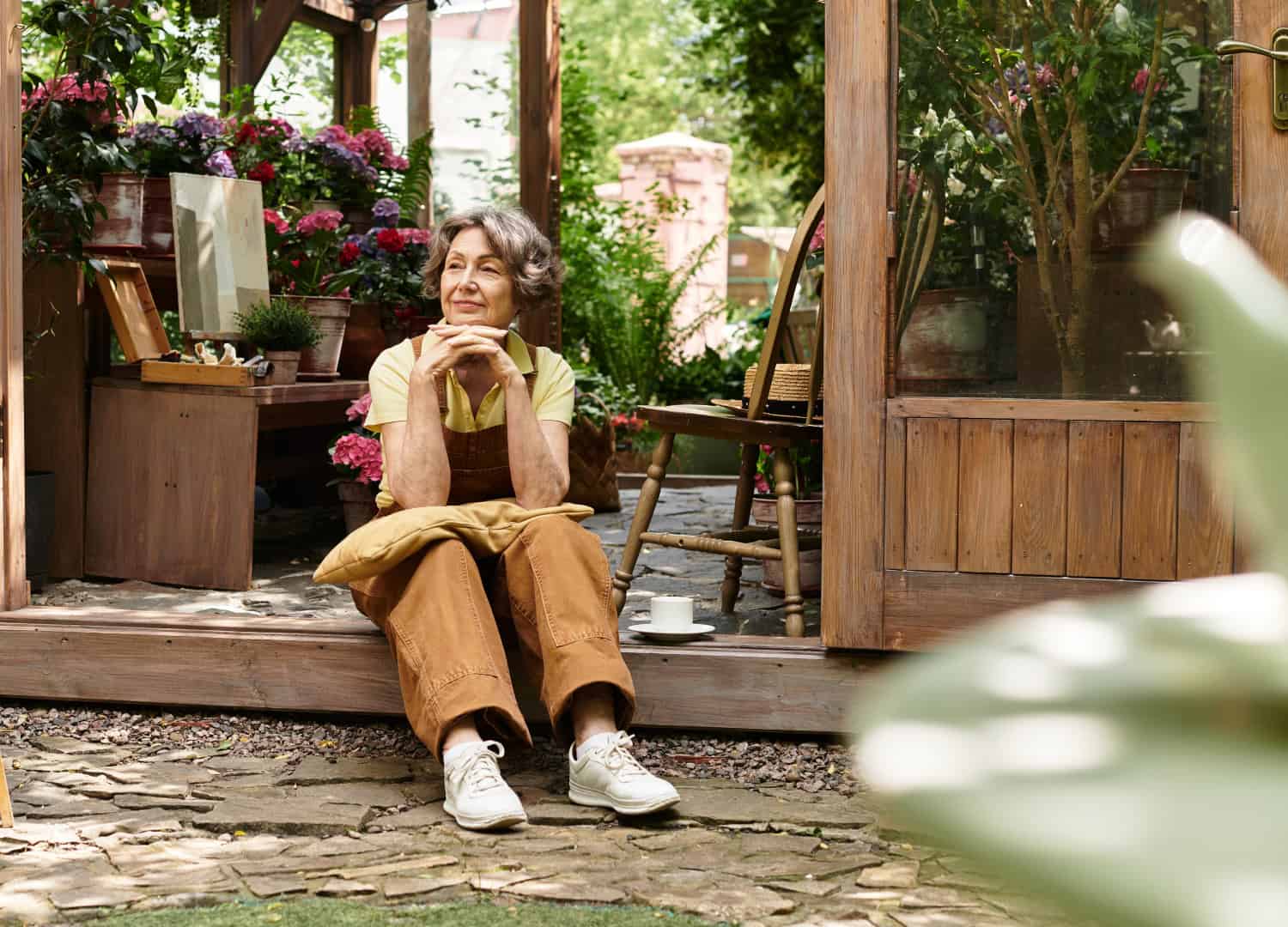 Senior woman enjoying tranquility in a lush garden setting surrounded by vibrant flowers