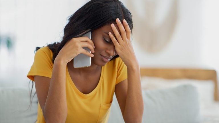 Worried black lady using mobile phone, concept of reaching out for help