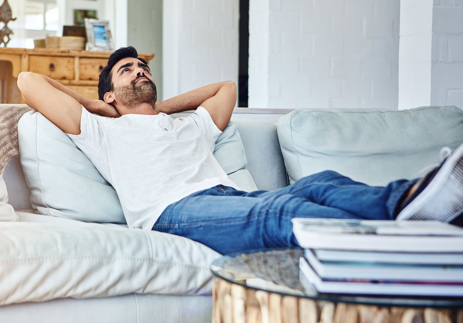 adult man leaning against a sofa in the living room, concept of rest, deep thinking