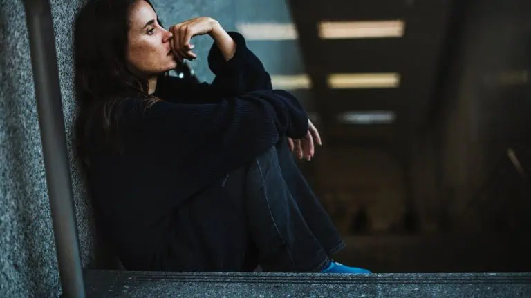 adult woman sitting on a stairwell looking depressed and struggling with anxiety