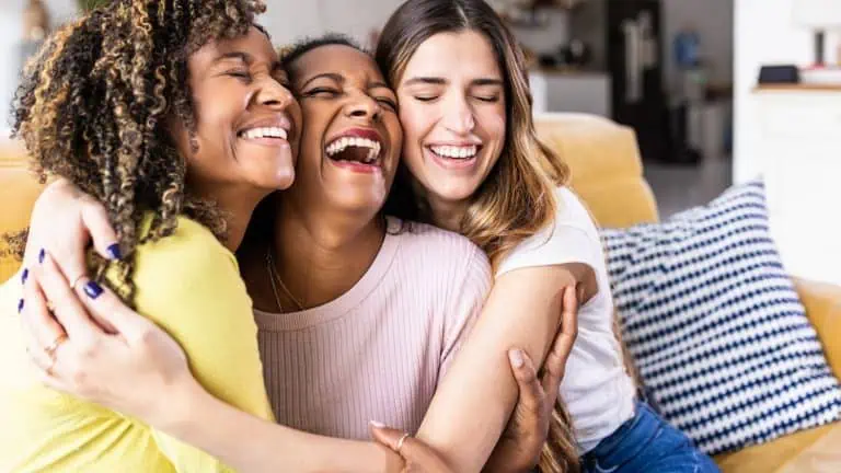 cheerful friends hugging and laughing with each other, concept of social skills