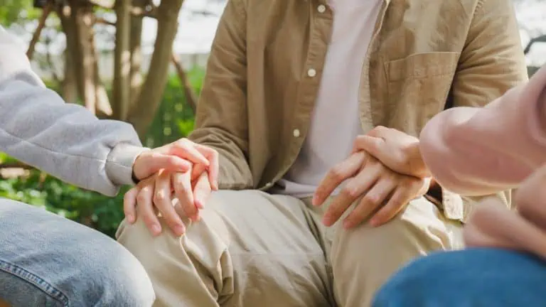 close up shot of family holding hands during family therapy counseling session