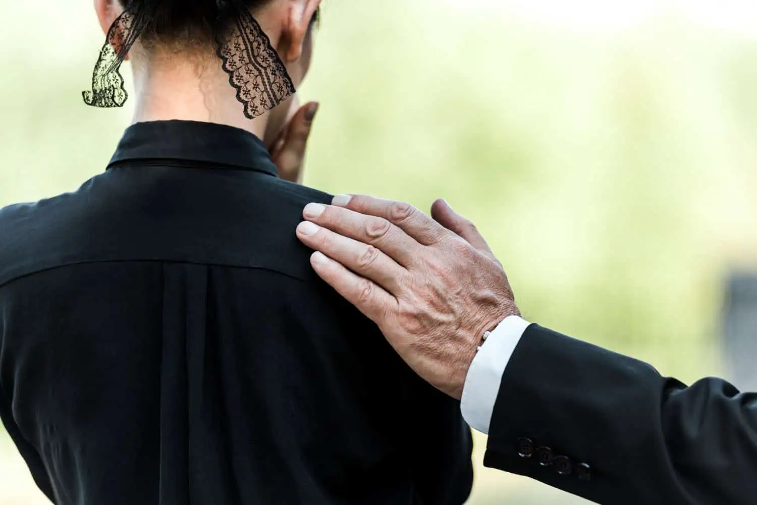 cropped view of a man's hand on a woman's shoulder, concept of support through grief