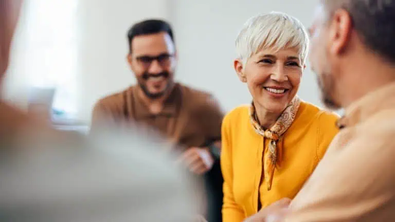 focused shot of a woman smiling and talking while in a group therapy session