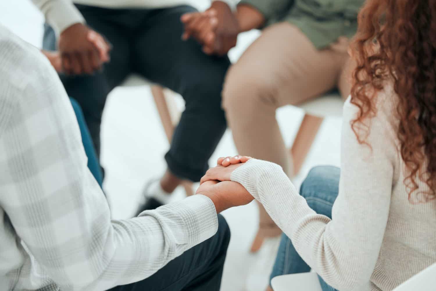 group of people sit in a circle holding hands, concept of group therapy