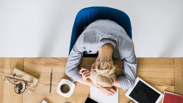 overhead view of tired businesswoman sleeping on workplace in office