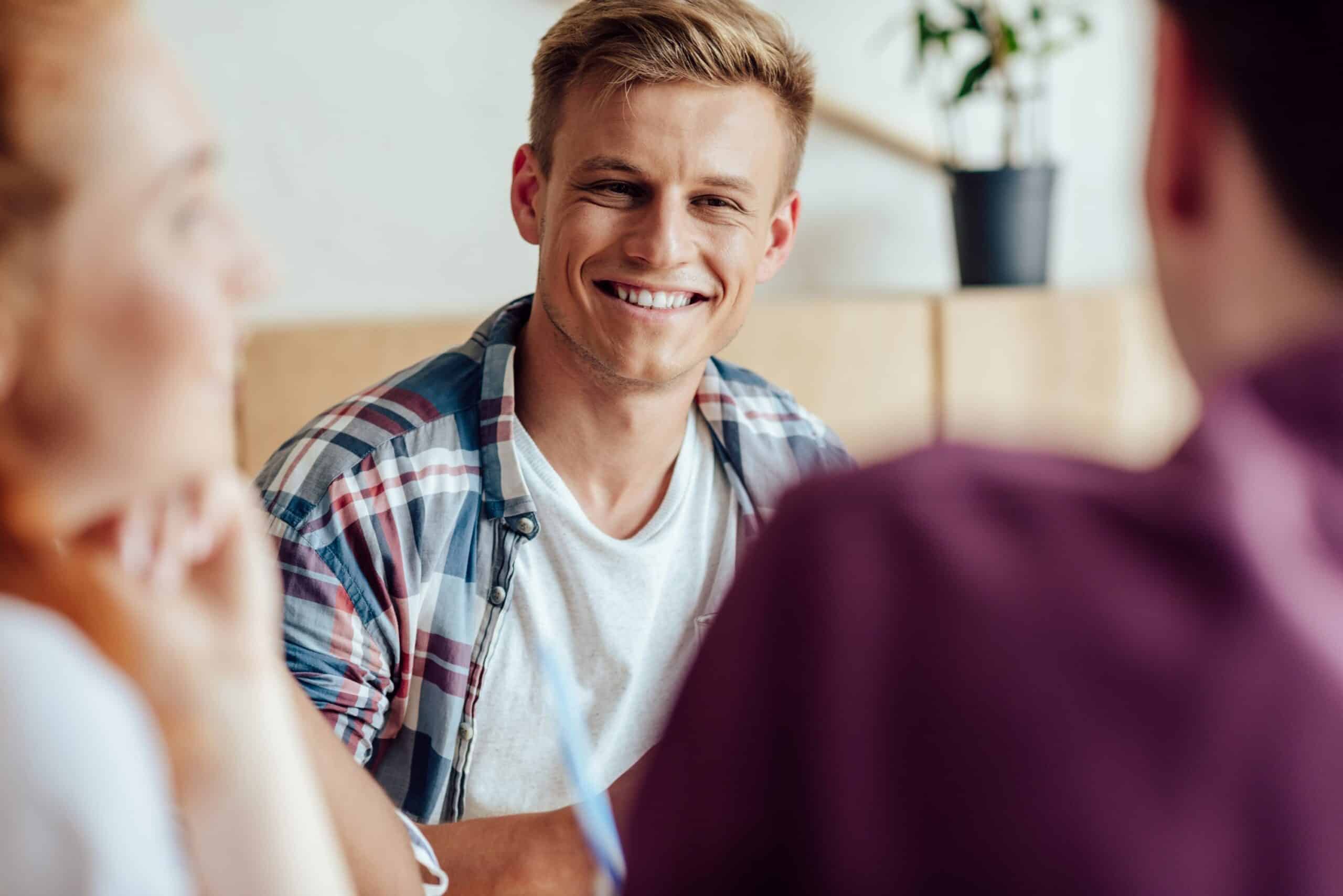 smiling young man looking at friends, concept of happy relationships