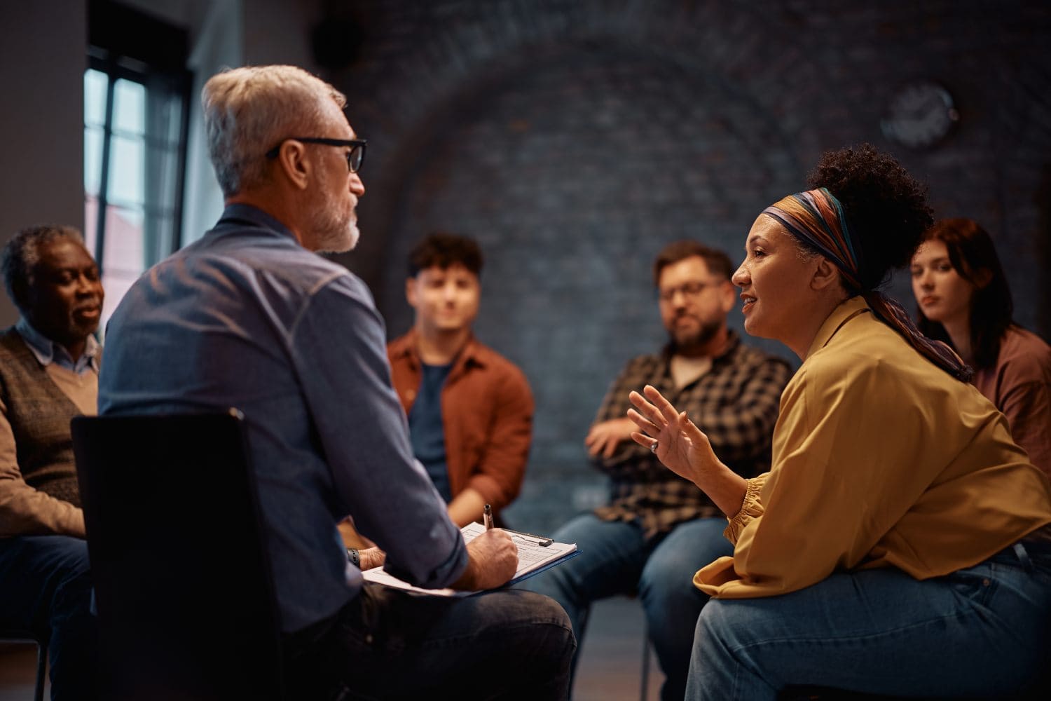 woman communicating with mental health counselor during group therapy at community center