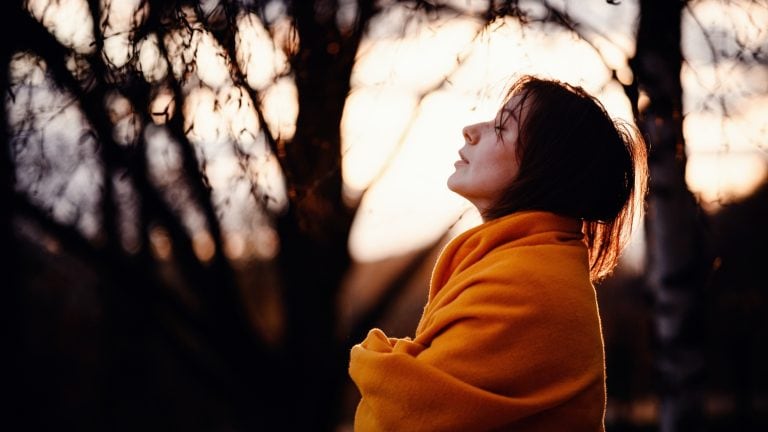 woman looking sad, standing outside wrapped in a blanket, concept of alone, mental health struggles