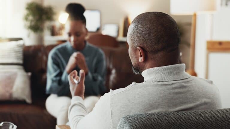 woman sits with her hands clasped, listening, concept of mental health, therapy, counseling, or personal growth