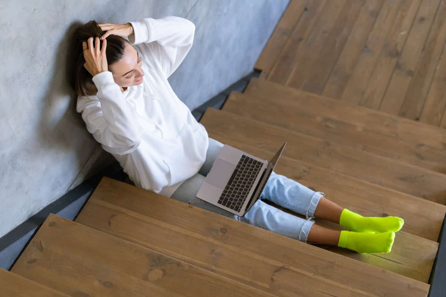 woman working on a laptop while sitting on the stairs