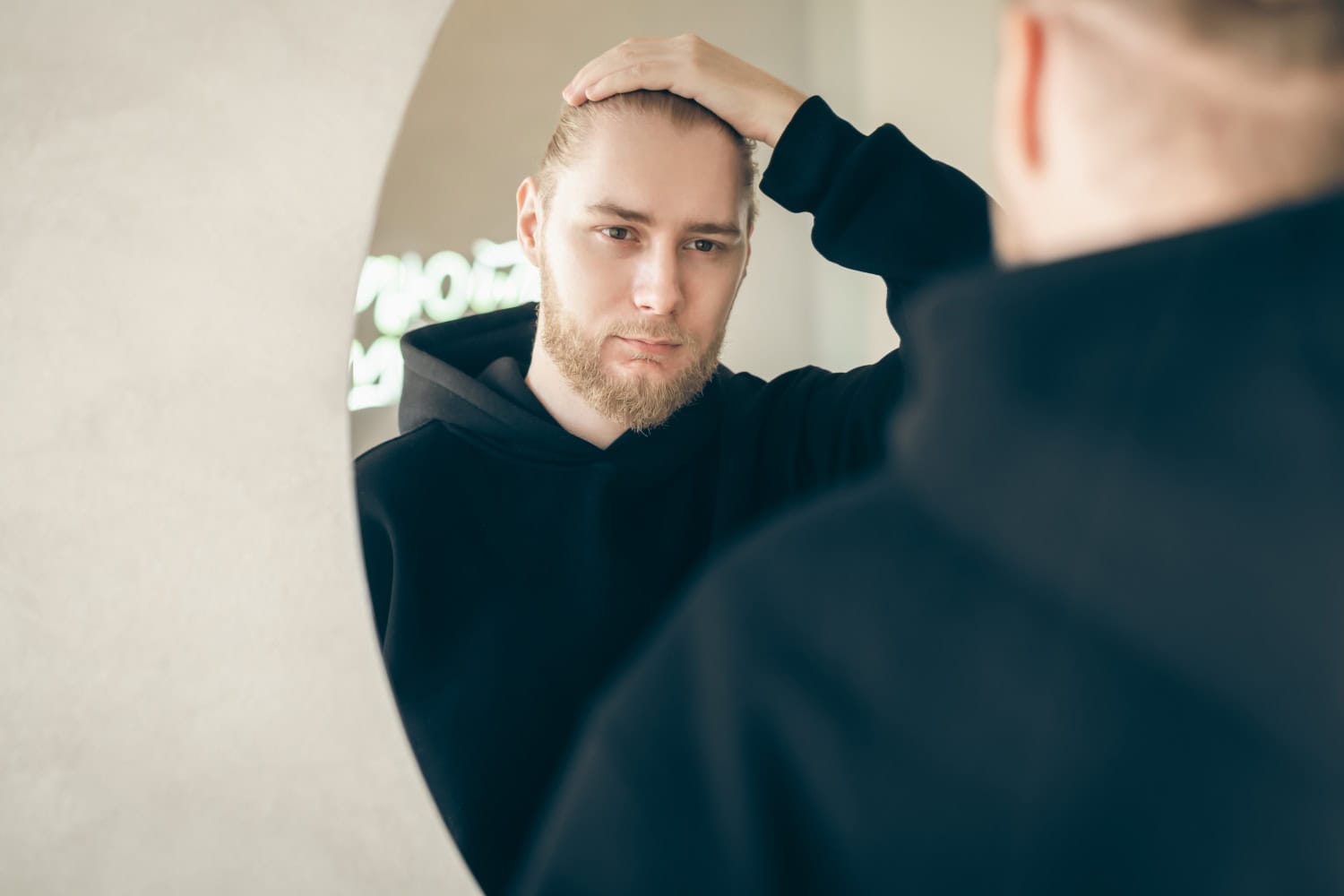 young man sadly looks at himself in the mirror