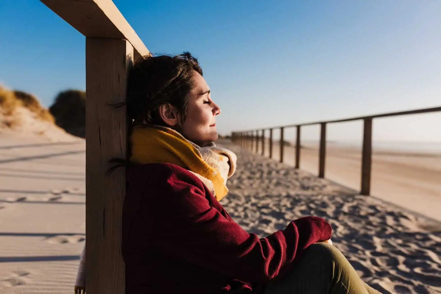young woman with eyes closed relaxing at beach at sunset